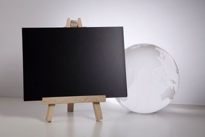 Close-up of blank blackboard and globe against white background