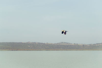 Man flying over sea against clear sky