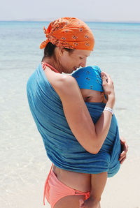 Rear view of woman holding her child at beach