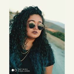 Portrait of young woman wearing sunglasses standing outdoors