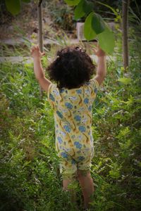 Rear view of girl standing amidst plants