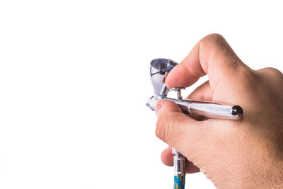 Close-up of hand holding camera over white background