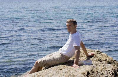 Man sitting on rock against seascape
