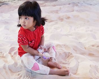 High angle view of baby girl sitting on sand