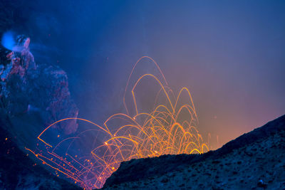 Firework display over sea against sky at night