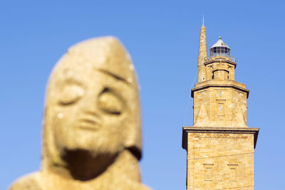 Tower of hercules and statue against clear blue sky