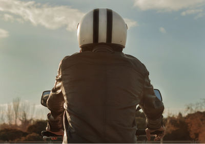 Rear view of man riding motorcycle against sky