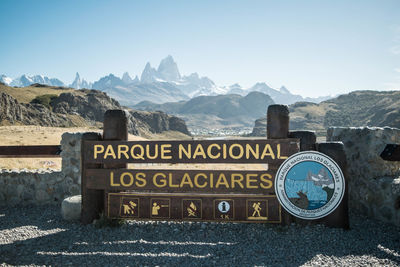Information sign on snowcapped mountains against clear sky