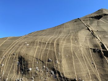 Low angle view of desert against clear blue sky