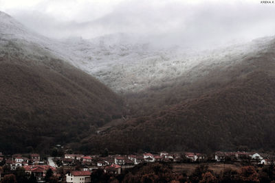 Scenic view of town by mountains against sky