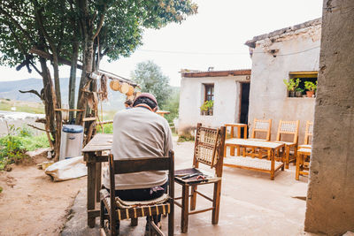 Rear view of man sitting on chair at table