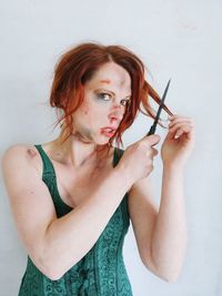 Portrait of young woman standing against wall