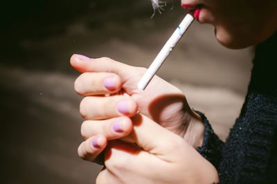 Close-up of young woman lighting cigarette