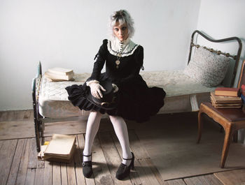 Portrait of woman wearing costume while sitting on bed at home