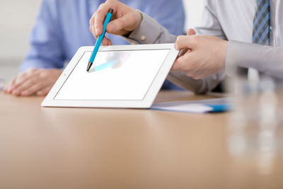 Midsection of man using mobile phone on table