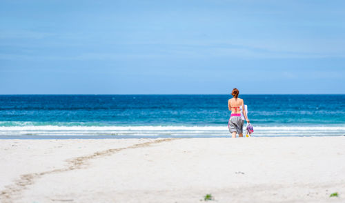 Rear view of woman walking on beach