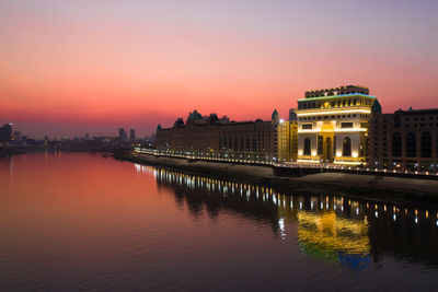 Reflection of illuminated buildings in lake at sunset