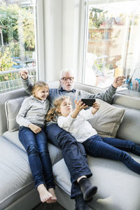 Two girls and grandfather on sofa taking a selfie