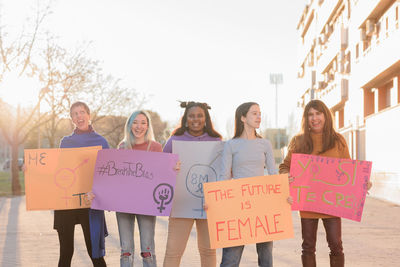 Cheerful females holding banners standing outdoors