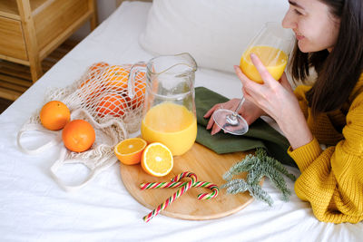 Happy woman drinking juice while lying on bed