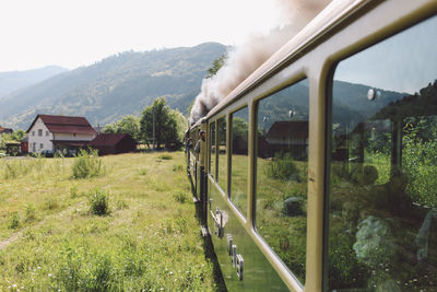 Train moving through landscape with mountain range in background