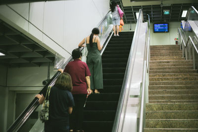 Rear view of people walking on escalator