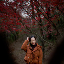 Young woman looking away while standing against trees