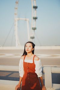 Portrait of young woman standing on footpath