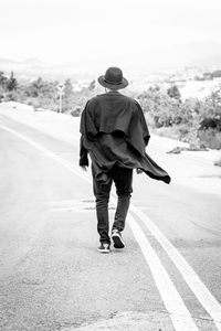 Rear view of man walking on road