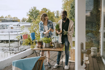 Young woman helping mature man doing gardening while standing on porch