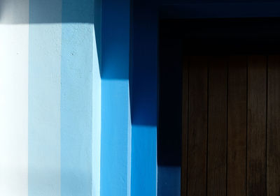 Close-up of blue columns and angular shadows on wall