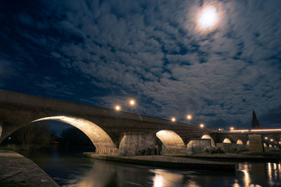 Arch bridge over river against sky at night