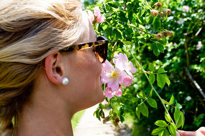 Close-up of woman smelling flowers on plant