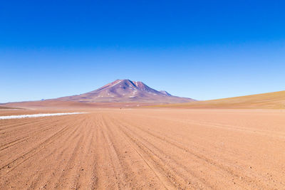 Scenic view of arid landscape against clear blue sky