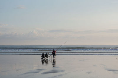 Man and dog on beach against sky