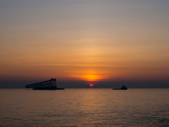 Silhouette boat sailing on sea against sky during sunset