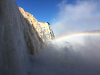 Low angle view of waterfall against sky during winter