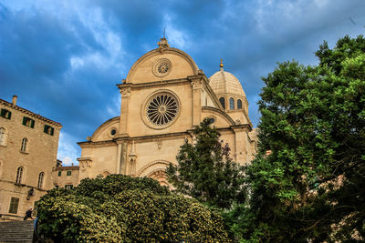 Low angle view of trees and building against sky