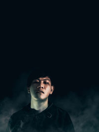 Portrait of young man against black background