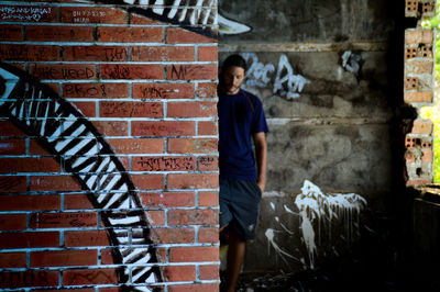 Close-up of graffiti on brick wall with man standing in background