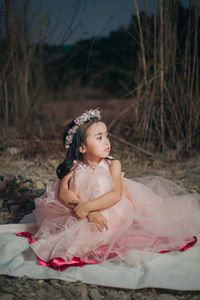 Woman looking away while sitting on land