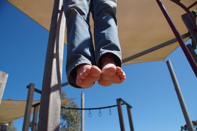 Low section of boy hanging on monkey bars at park