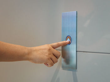 Cropped hand of person pressing elevator button on wall