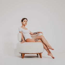 Young woman sitting on sofa against white background