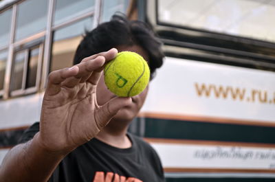 Close-up of man holding ball against window