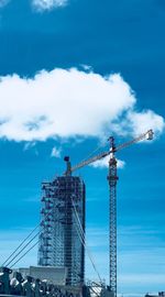 Low angle view of crane at construction site against sky