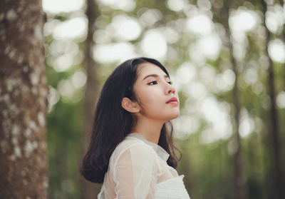Close-up of young woman against trees