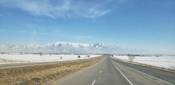 Road by snowcapped mountains against sky