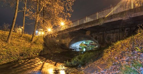 Illuminated bridge over street in city at night