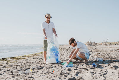 Men picking up plastic bottles at beach